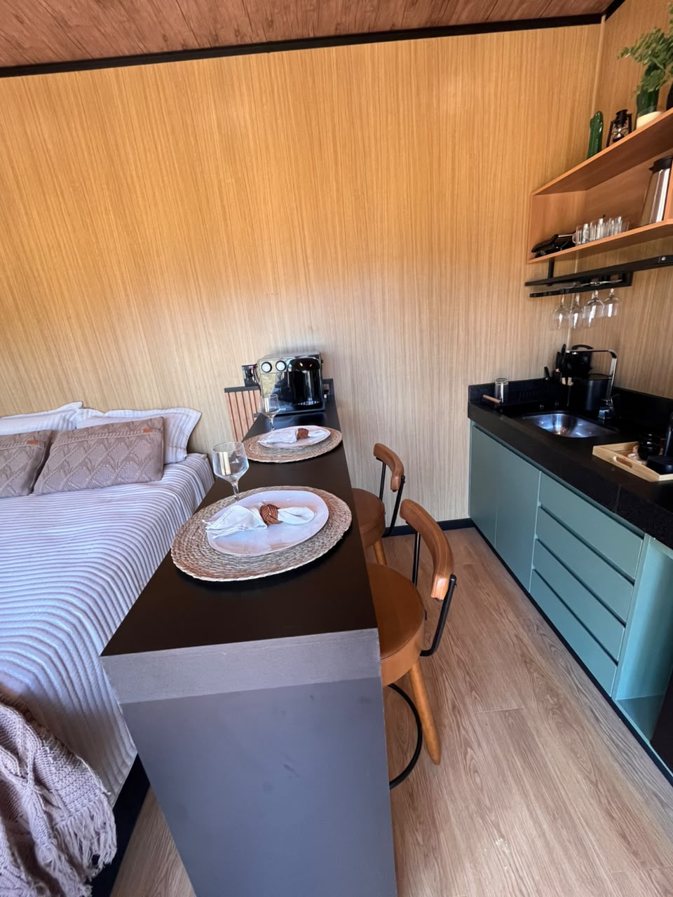 Bancada preta com mesa posta e cozinha compacta ao fundo