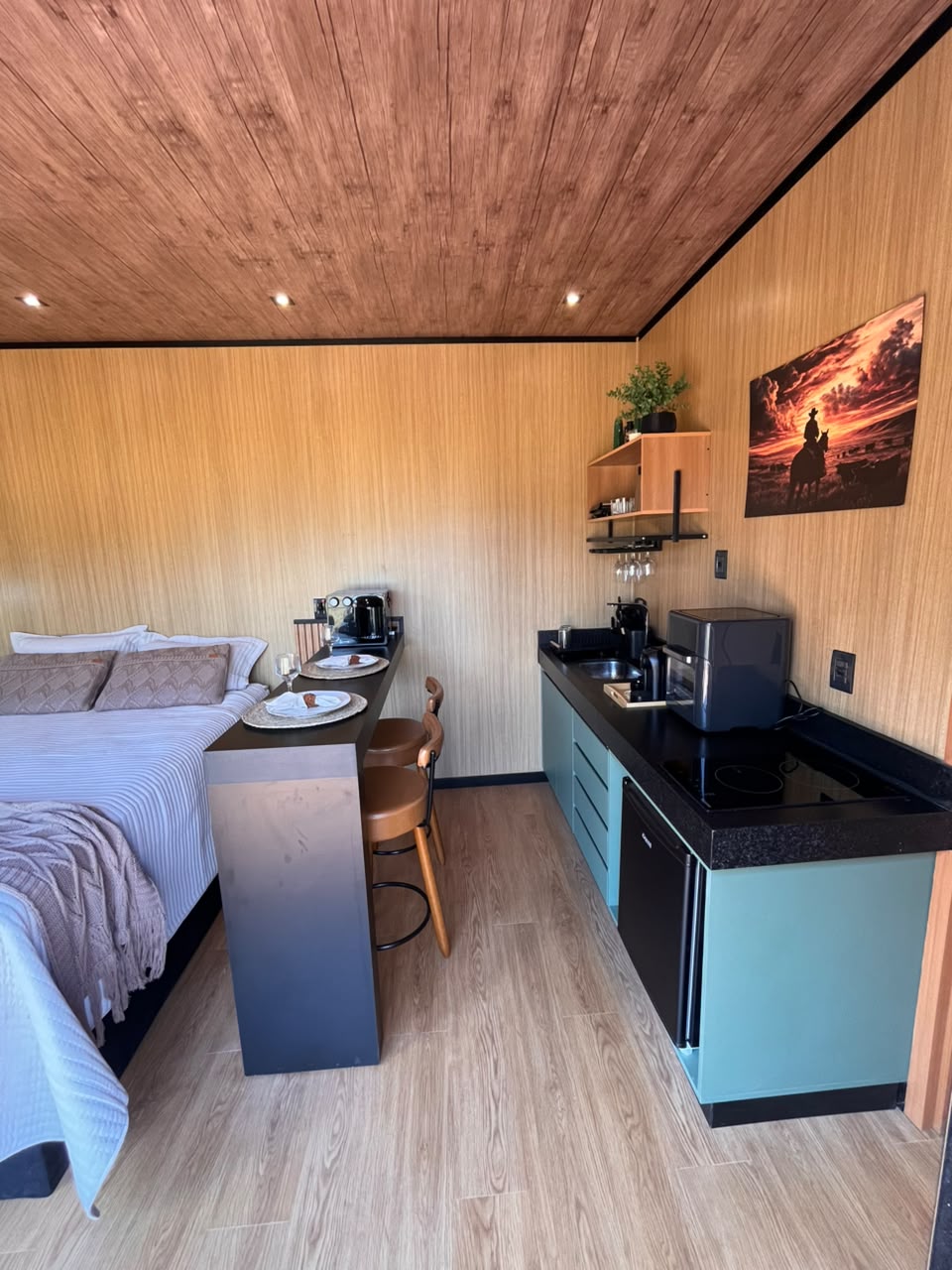 Interior completo da unidade com cama, bancada e cozinha compacta